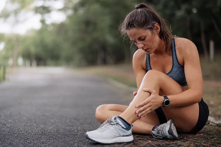 Woman holding leg muscle pain outdoors
